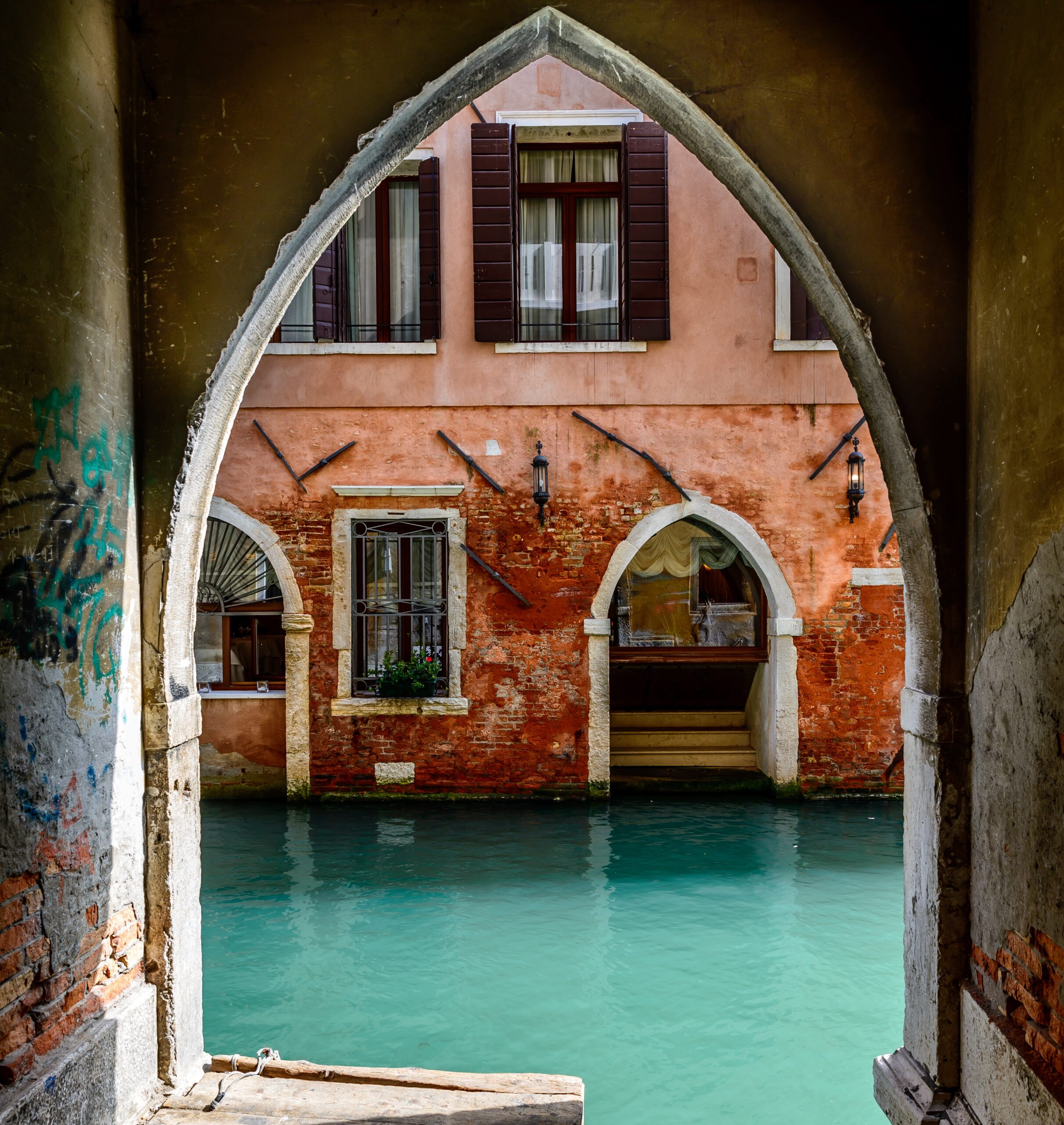 Old arch near the canal and an ancient red house with open windows Papà che tiene in braccio la figlia e la mamma di fianco sorride